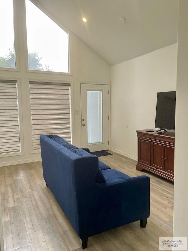 living area with lofted ceiling, light wood-style flooring, and baseboards