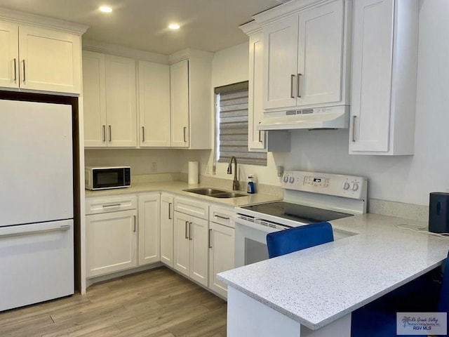 kitchen with white appliances, under cabinet range hood, and white cabinets