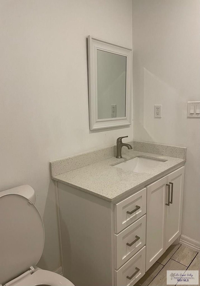 bathroom featuring baseboards, vanity, and toilet