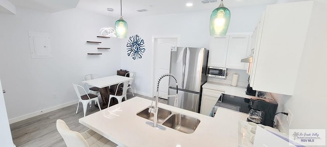 kitchen featuring white cabinets, hanging light fixtures, sink, and appliances with stainless steel finishes