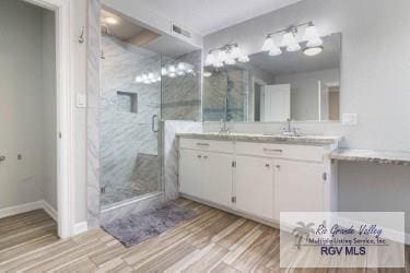 bathroom featuring hardwood / wood-style floors, vanity, and an enclosed shower