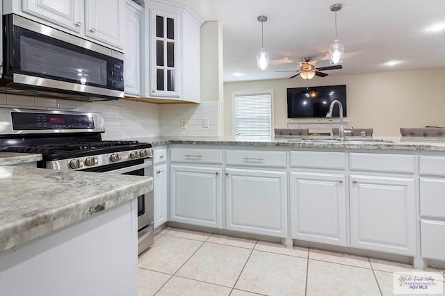 kitchen with decorative backsplash, stainless steel appliances, sink, white cabinets, and light tile patterned flooring