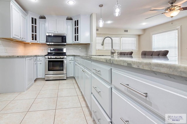 kitchen with sink, hanging light fixtures, tasteful backsplash, white cabinets, and appliances with stainless steel finishes