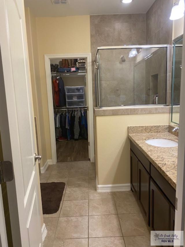 bathroom with tile patterned flooring, vanity, and walk in shower