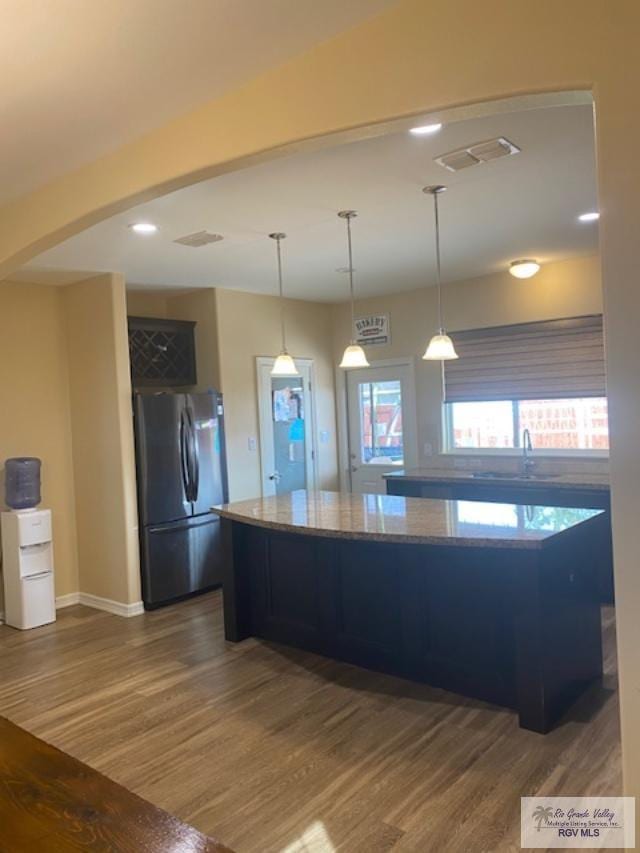 kitchen featuring stainless steel fridge, decorative light fixtures, dark wood-type flooring, and sink