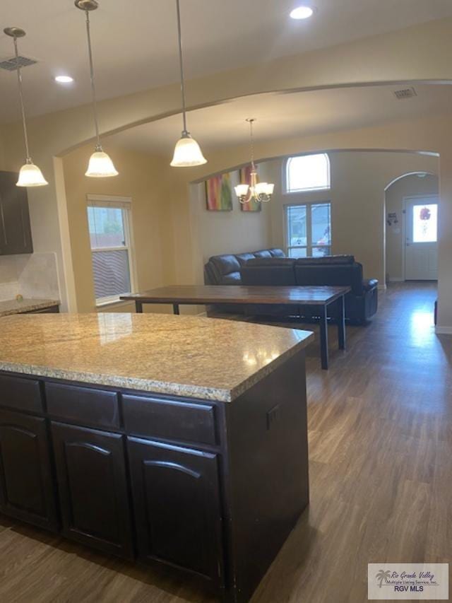 kitchen with dark hardwood / wood-style flooring, decorative light fixtures, vaulted ceiling, and a healthy amount of sunlight