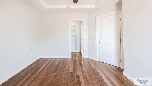 unfurnished bedroom featuring wood finished floors, a ceiling fan, and baseboards