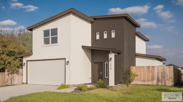 view of front of property featuring a garage, fence, driveway, stucco siding, and a front yard