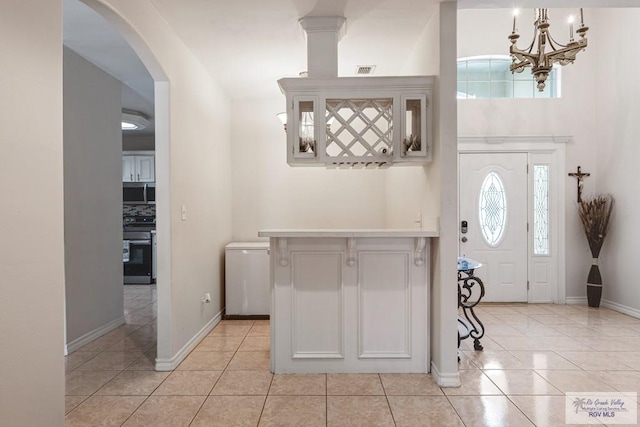 entryway featuring visible vents, light tile patterned flooring, baseboards, and arched walkways