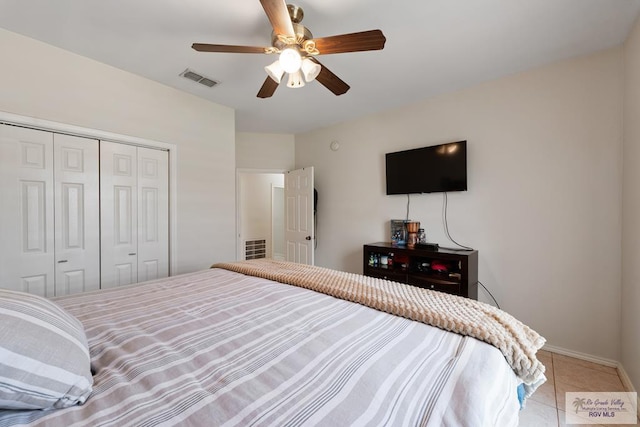 bedroom featuring visible vents, tile patterned floors, baseboards, ceiling fan, and a closet