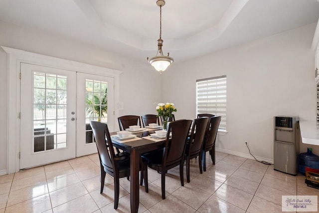 dining room with a tray ceiling, baseboards, light tile patterned flooring, and french doors