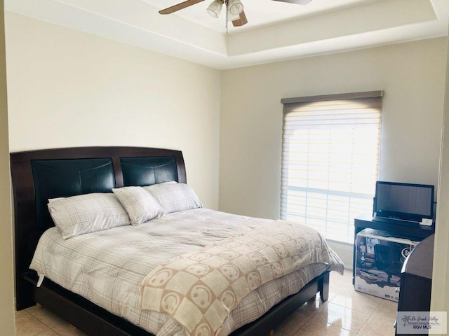 bedroom featuring a raised ceiling, light tile patterned flooring, and a ceiling fan