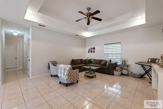 living area with a raised ceiling, light tile patterned flooring, and visible vents