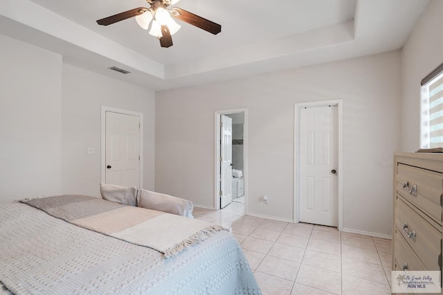 bedroom with a tray ceiling, light tile patterned floors, baseboards, and visible vents