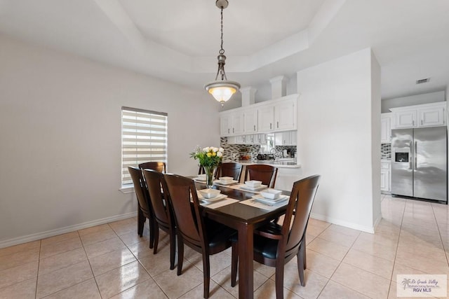 dining area featuring a tray ceiling, light tile patterned floors, baseboards, and visible vents