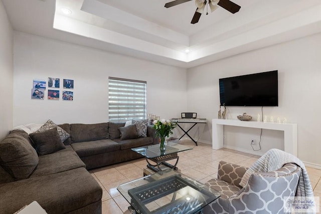 tiled living room featuring baseboards, a raised ceiling, and ceiling fan