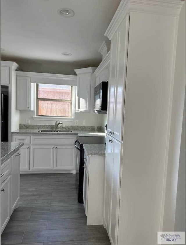 kitchen featuring sink, white cabinetry, black appliances, light stone countertops, and dark hardwood / wood-style flooring