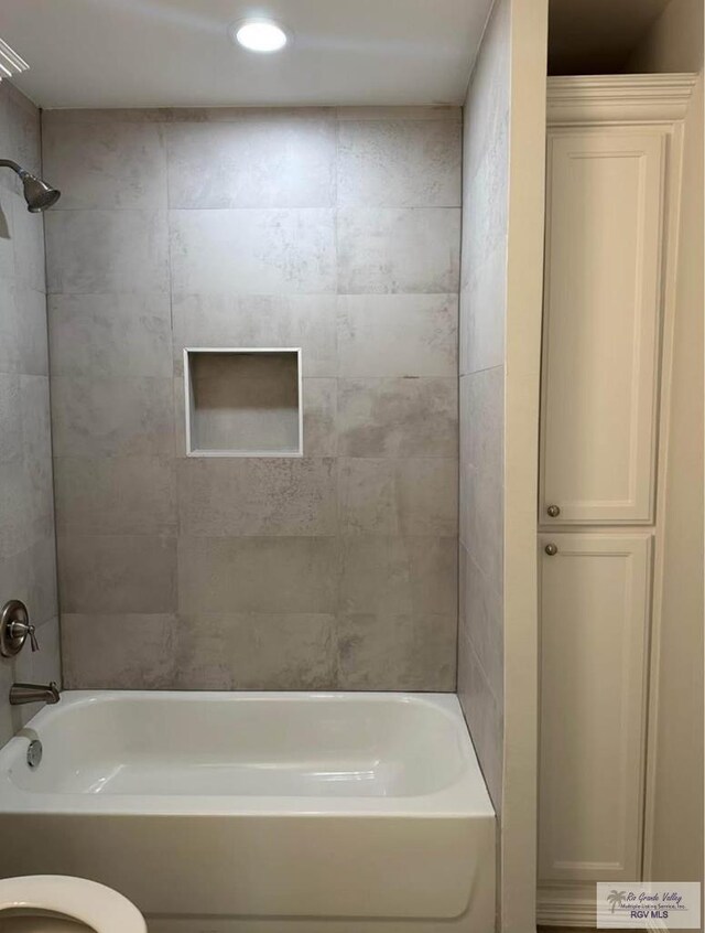 bathroom with tiled shower / bath and toilet