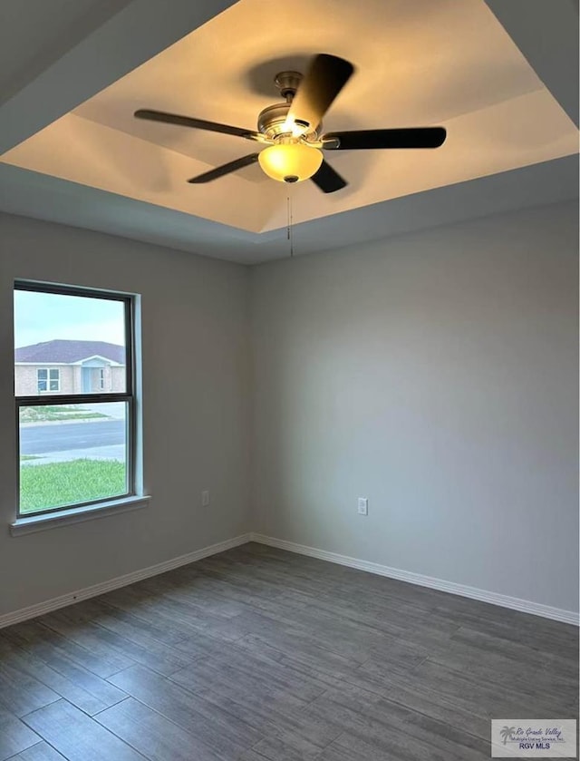 unfurnished room featuring ceiling fan, dark hardwood / wood-style flooring, and a raised ceiling