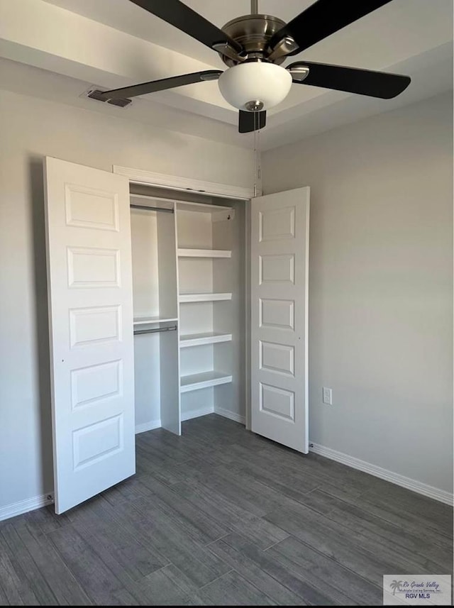 unfurnished bedroom with dark wood-type flooring, ceiling fan, and a closet