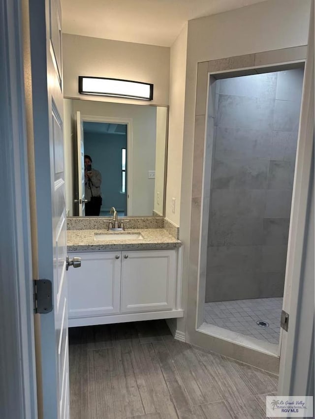 bathroom with vanity, wood-type flooring, and a tile shower