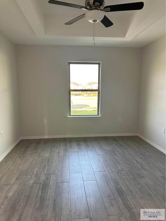 empty room featuring hardwood / wood-style flooring, ceiling fan, and a raised ceiling