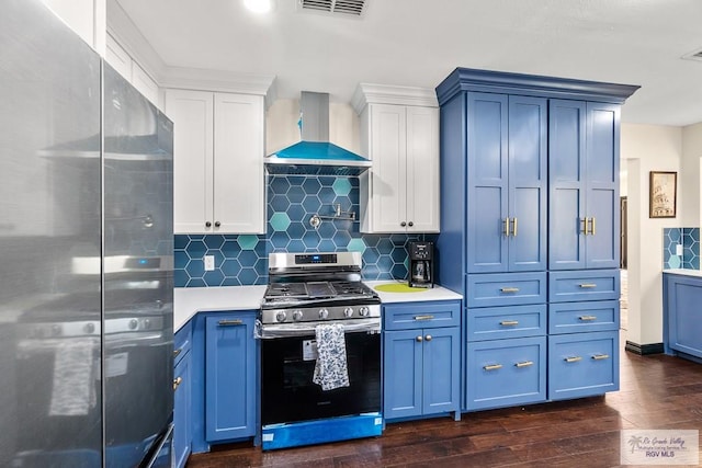 kitchen featuring dark wood-type flooring, blue cabinetry, wall chimney range hood, appliances with stainless steel finishes, and light countertops