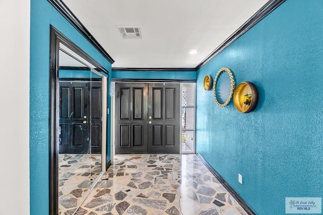 foyer entrance with stone tile floors, visible vents, crown molding, and a textured wall