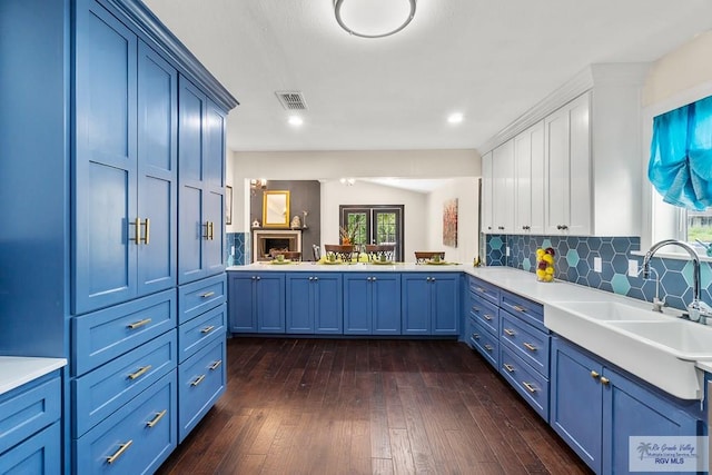 kitchen featuring dark wood finished floors, light countertops, blue cabinets, and a sink