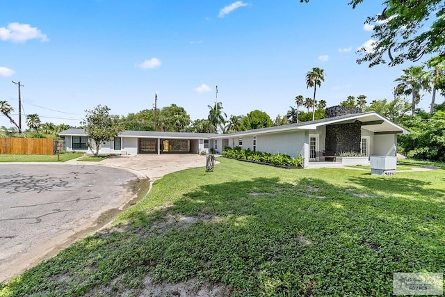 view of front facade with a carport, fence, a front lawn, and driveway