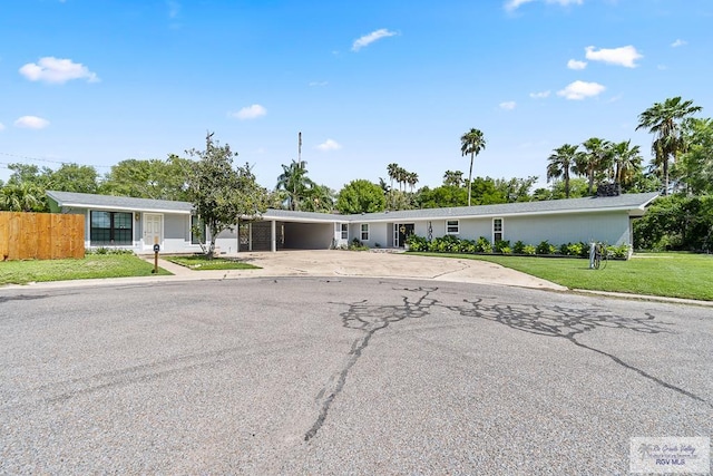 ranch-style home featuring an attached carport, a front lawn, concrete driveway, and fence