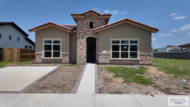 view of front facade with fence, stucco siding, and a tile roof