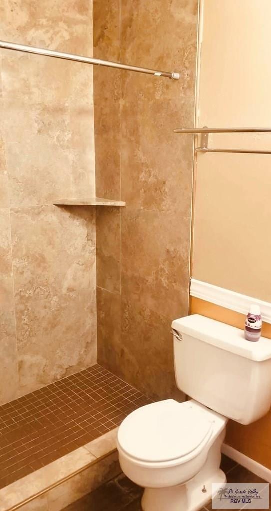 bathroom with a tile shower, tile patterned flooring, and toilet