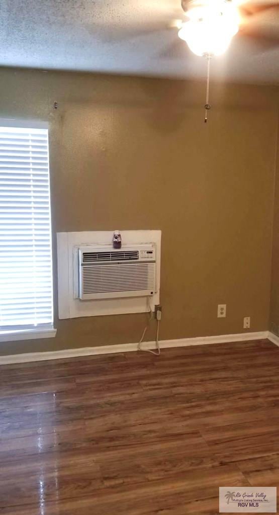unfurnished room with dark hardwood / wood-style floors, a wall mounted AC, and ceiling fan