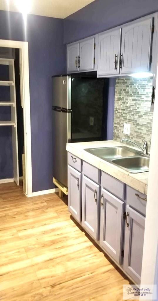 kitchen featuring gray cabinetry, sink, light hardwood / wood-style floors, and stainless steel refrigerator