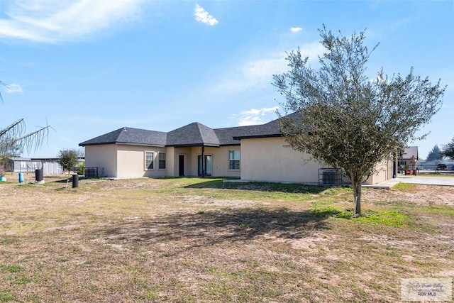 view of front of home featuring a garage, a front lawn, central AC unit, and stucco siding