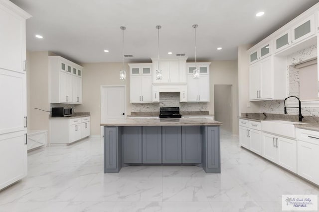 kitchen featuring marble finish floor, white cabinetry, a kitchen island, a sink, and black / electric stove