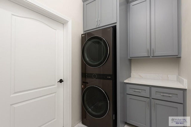 laundry area with stacked washer / dryer and cabinet space