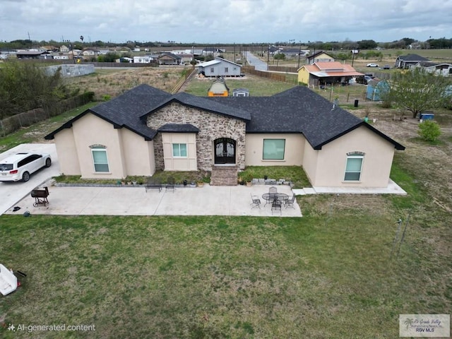 view of front of house with stone siding, a front yard, a patio area, and stucco siding