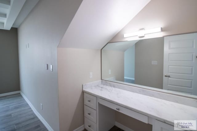 bathroom featuring vanity, wood-type flooring, and vaulted ceiling