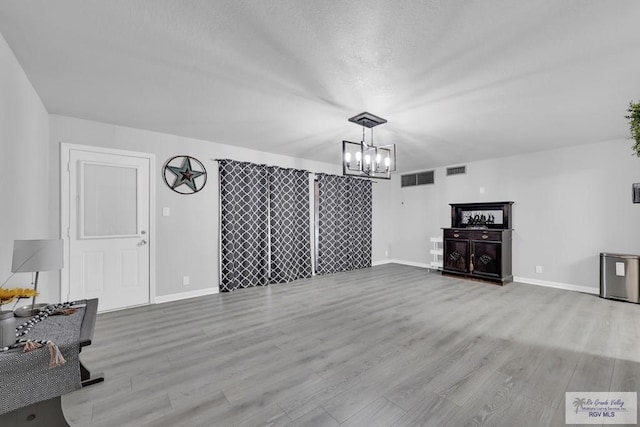 unfurnished living room featuring an inviting chandelier and light hardwood / wood-style floors