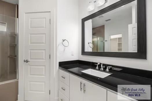 bathroom with combined bath / shower with glass door and vanity