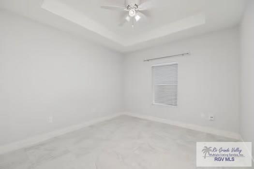 spare room featuring a tray ceiling and ceiling fan