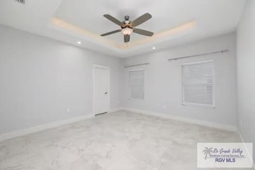 empty room featuring a tray ceiling and ceiling fan