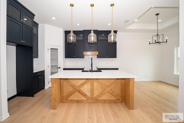 2409 Brown Pelican Ln, Harlingen, TX 78552 - kitchen featuring light wood-type flooring, decorative backsplash, light countertops, a kitchen island with sink, and recessed lighting
