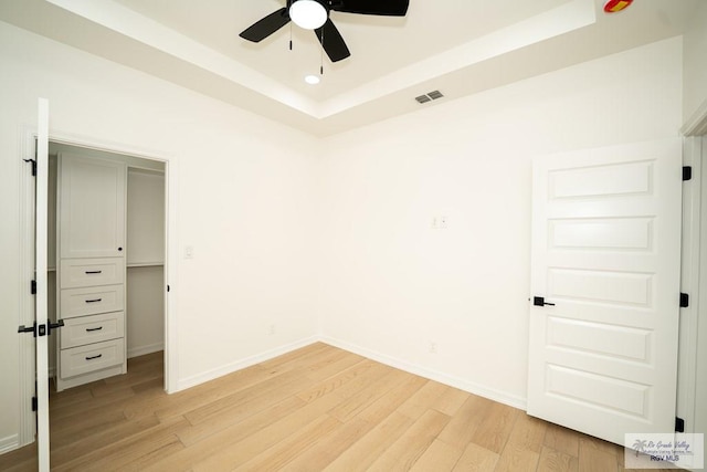 2409 Brown Pelican Ln, Harlingen, TX 78552 - unfurnished bedroom featuring light wood-type flooring, a raised ceiling, and ceiling fan