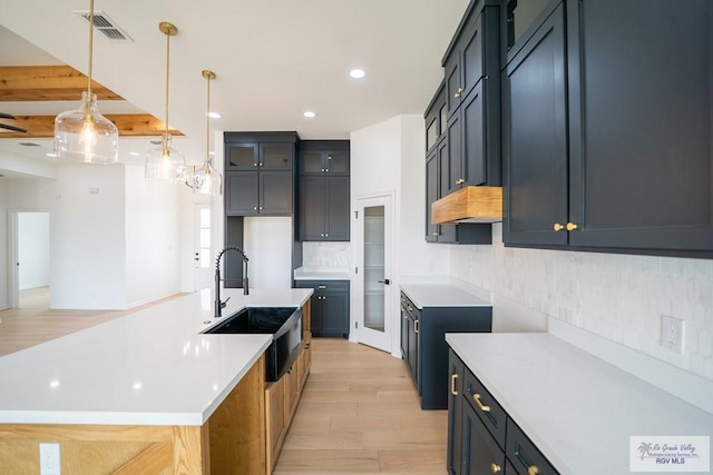 2409 Brown Pelican Ln, Harlingen, TX 78552 - kitchen featuring light wood-style flooring, tasteful backsplash, an island with sink, recessed lighting, and hanging light fixtures
