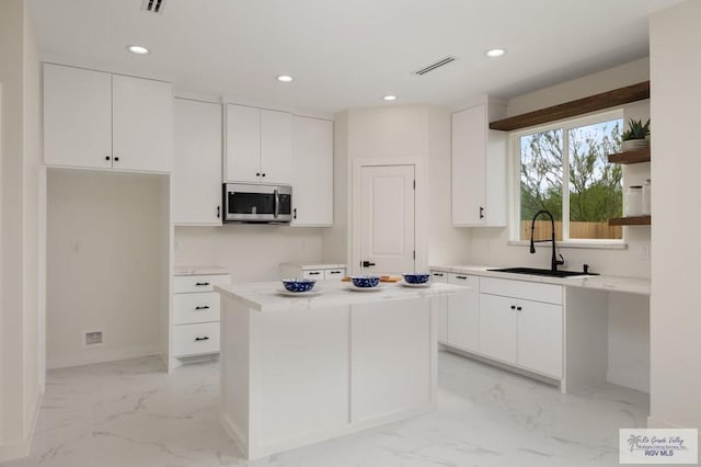 kitchen featuring stainless steel microwave, visible vents, a sink, marble finish floor, and open shelves