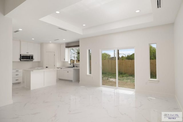 unfurnished living room featuring recessed lighting, a tray ceiling, and a sink