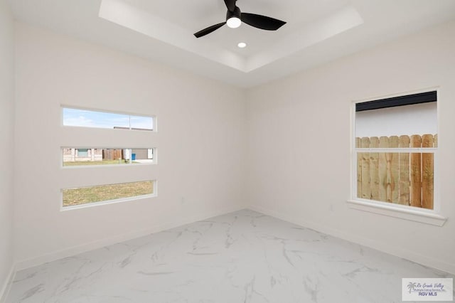 unfurnished room featuring a tray ceiling, plenty of natural light, and baseboards